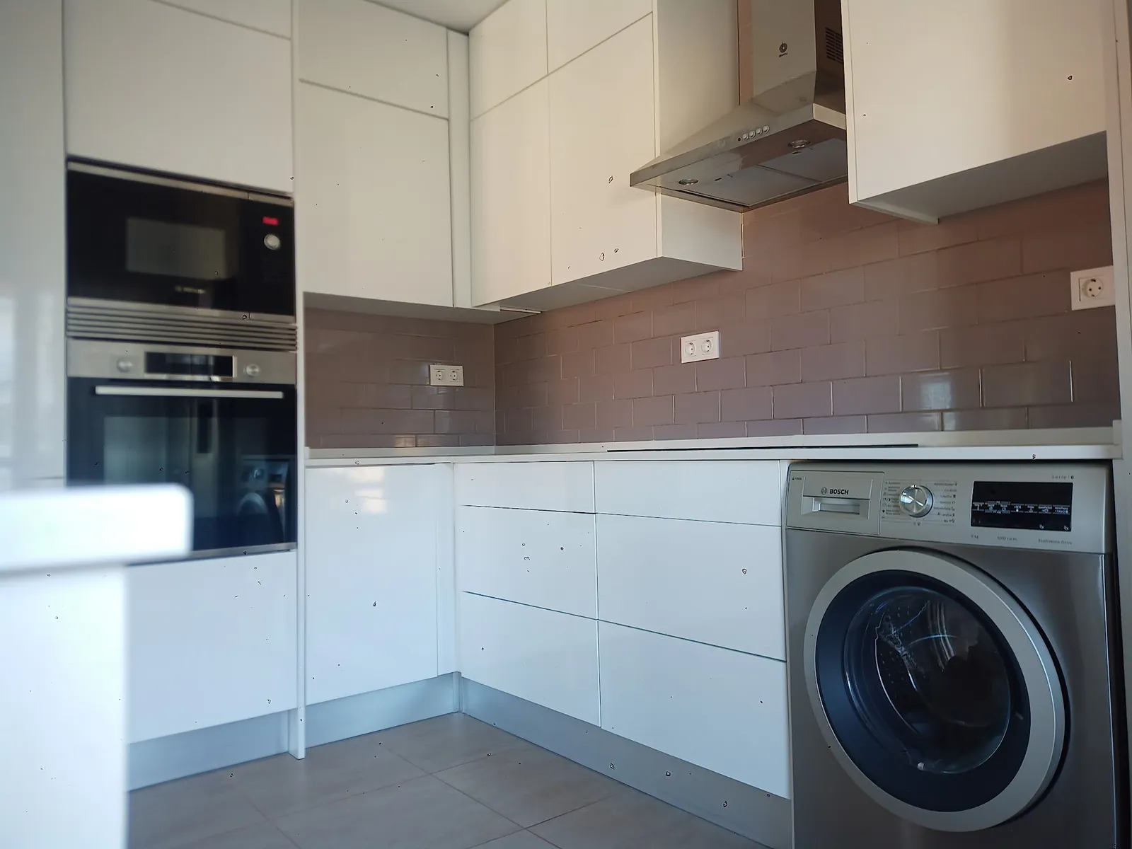 Cozinha branca com forno, micro-ondas, exaustor e máquina de lavar roupa