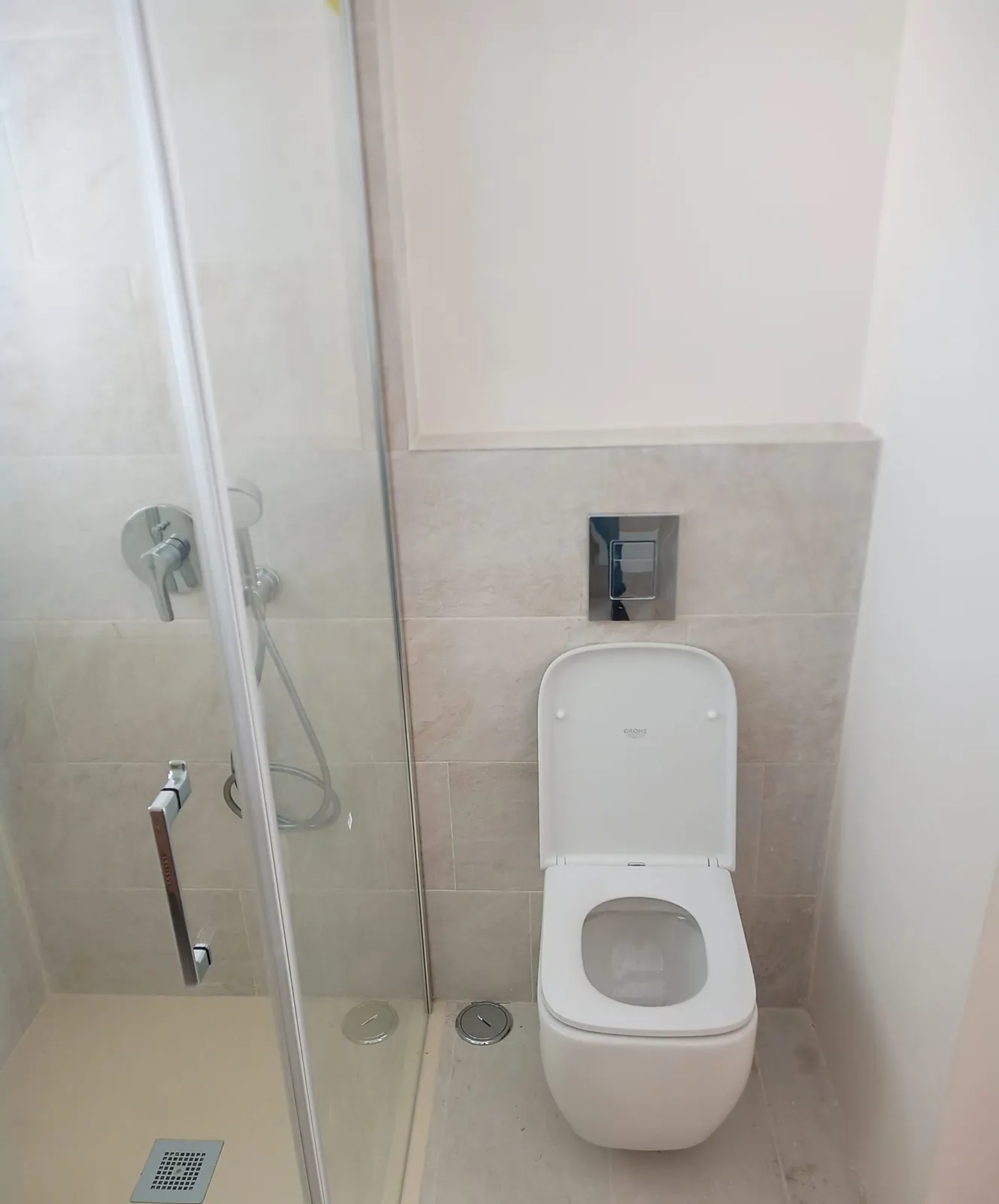 Casa de banho clara com duche de porta de vidro, misturadora e sanita