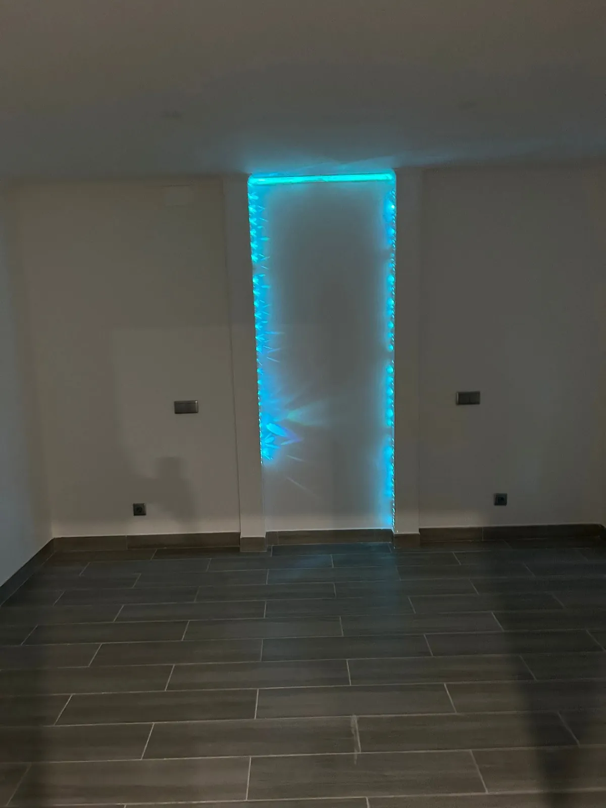 Sala vazia às escuras com uma luz azul LED a contornar uma porta