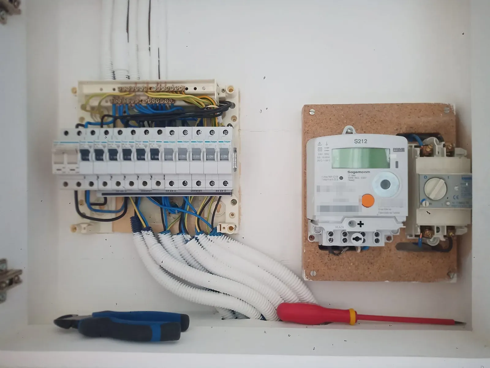 Quadro elétrico com disjuntores e cabos arrumados, ao lado do contador da luz