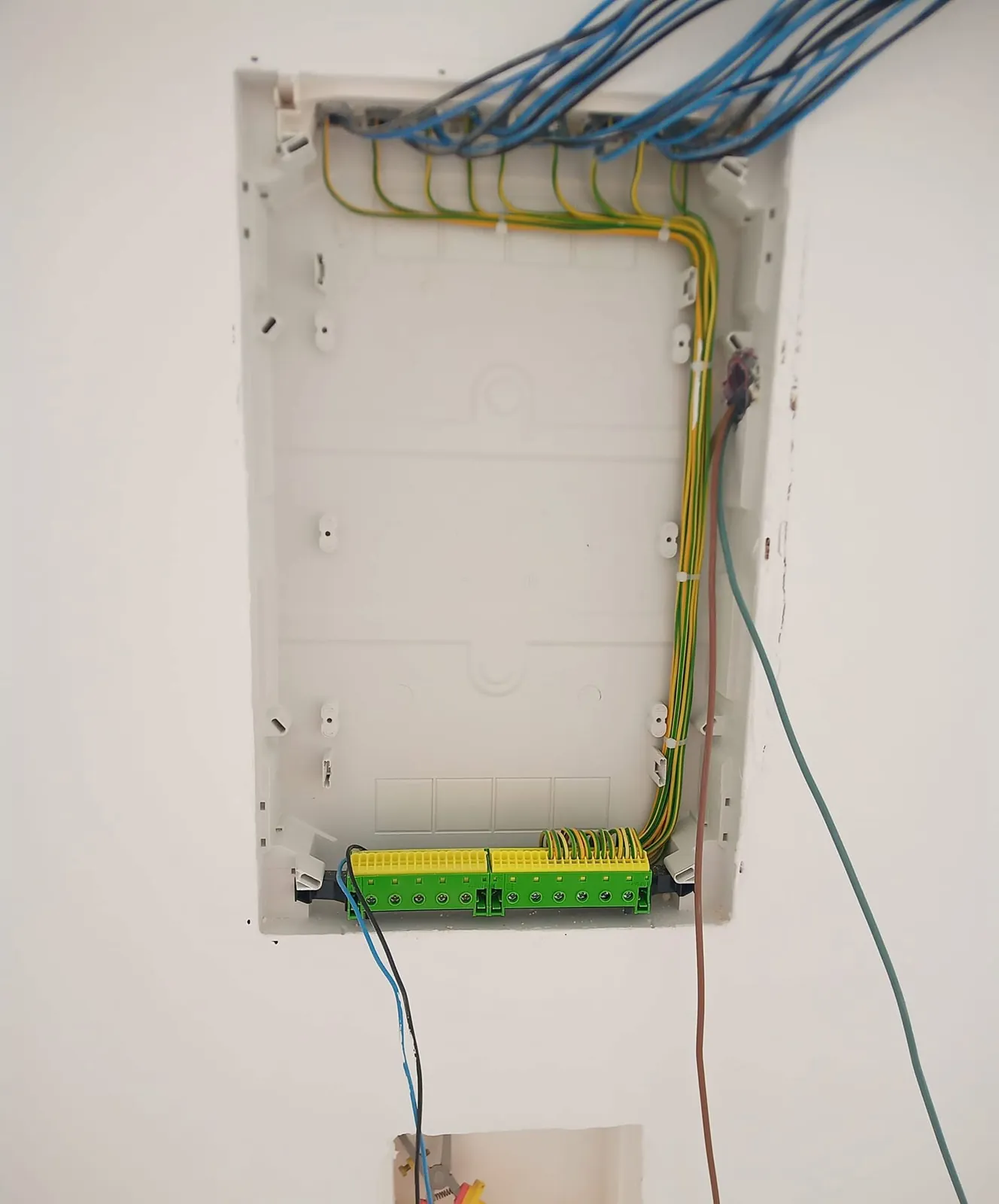 Caixa de quadro elétrico na parede, com os cabos a entrar por cima, ainda sem disjuntores