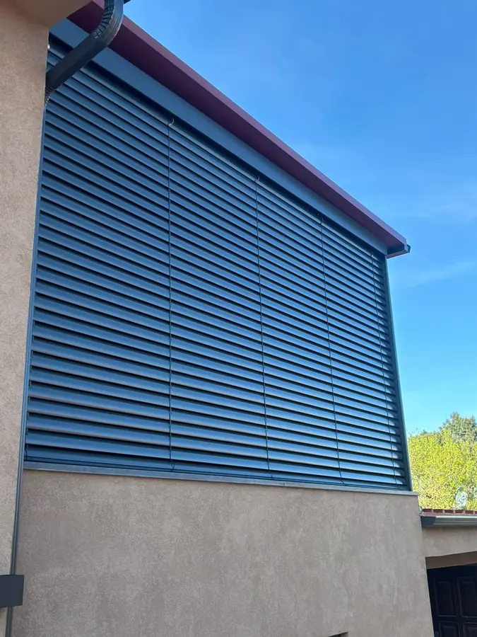Brisa solar cinzenta numa fachada, sob céu azul