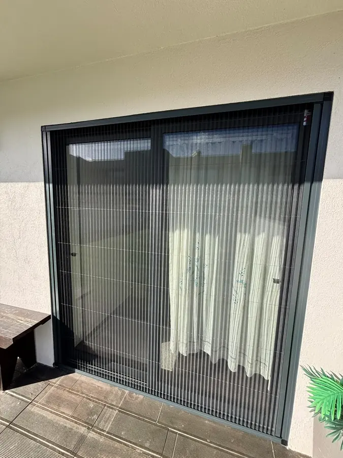 Mosquiteira plissada fechada numa porta de correr para o terraço