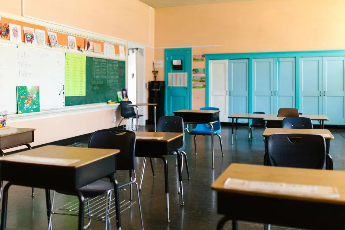 Sala de estudo com secretárias, quadro verde e armários azuis