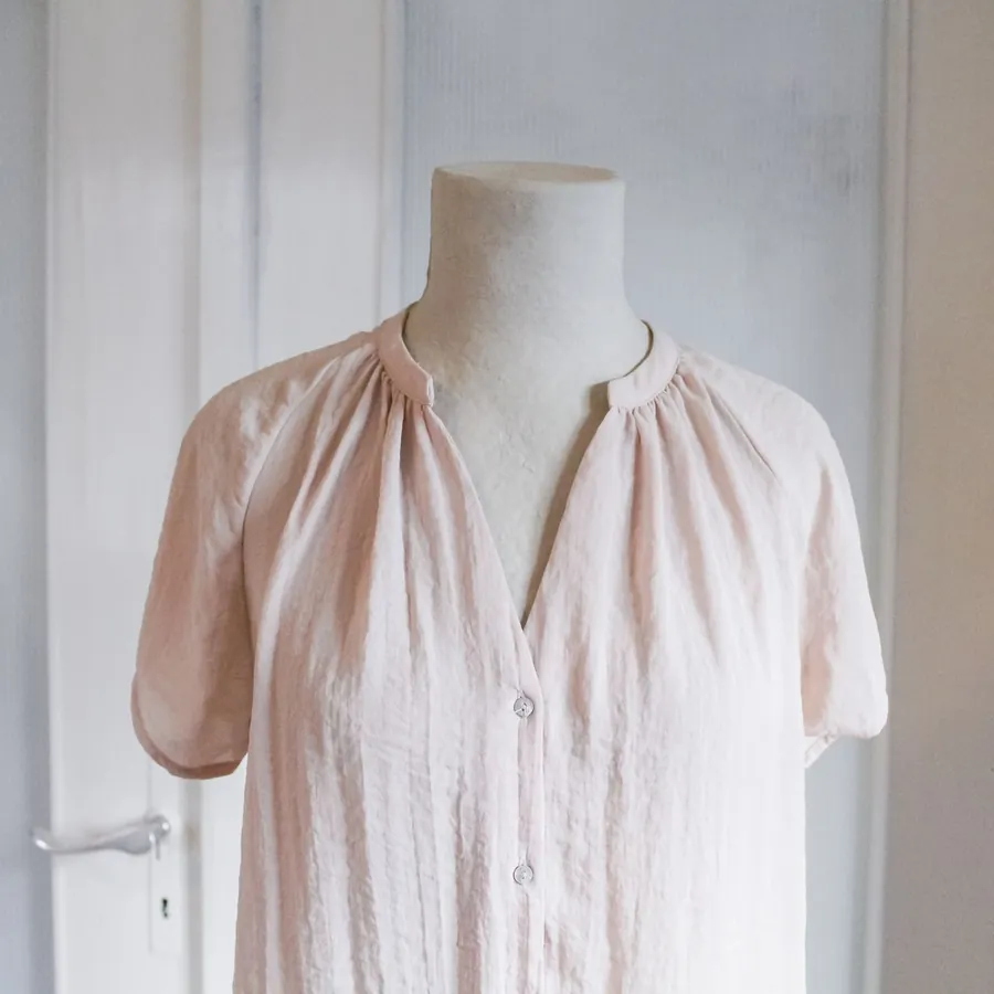 Blusa de seda em rosa-pó num manequim do atelier.