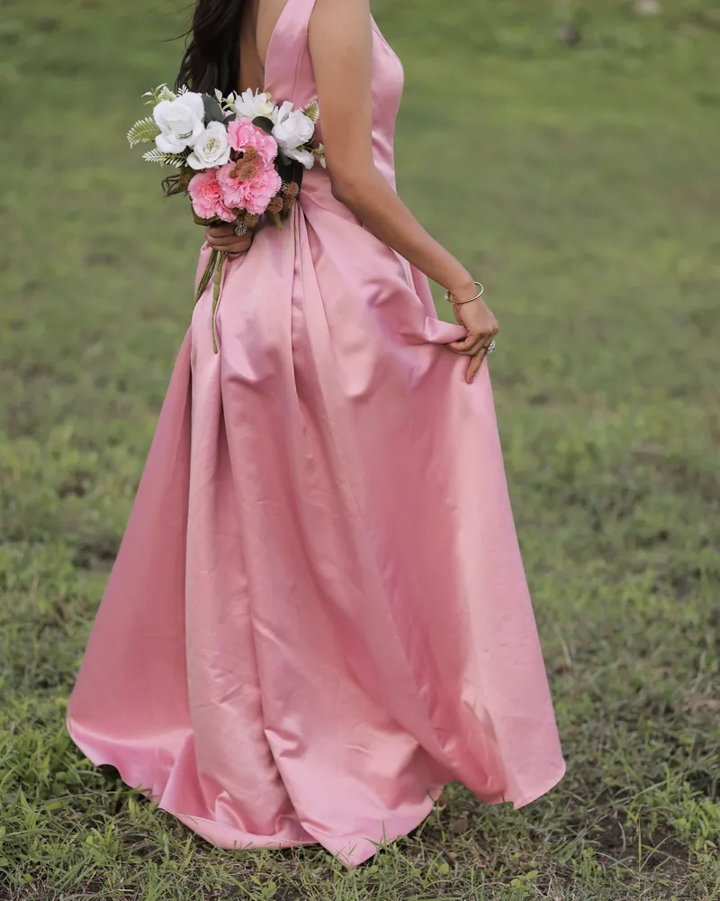 Modelo BRISA: vestido comprido de cetim rosa, visto de costas, num relvado.