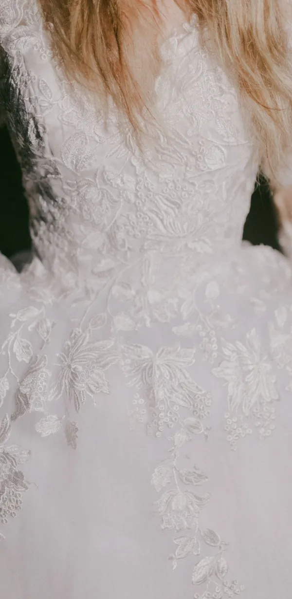 Vestido de noiva Camélia: corpete de renda floral com decote em bico e manga comprida.