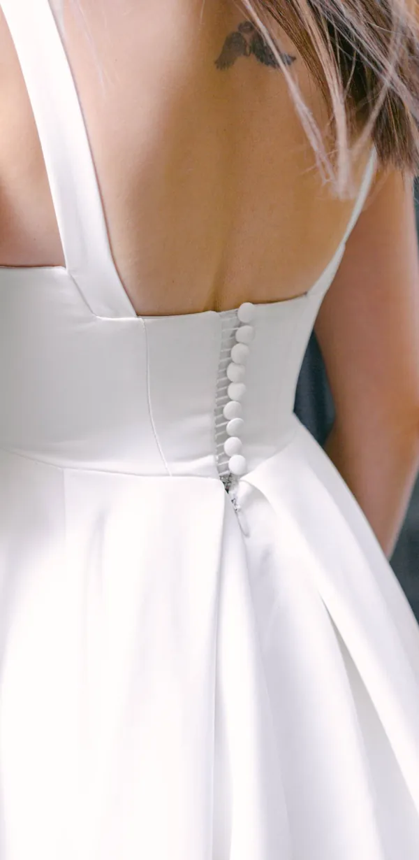 Vestido de noiva Magnólia de costas: cetim liso, alças largas e botões forrados.